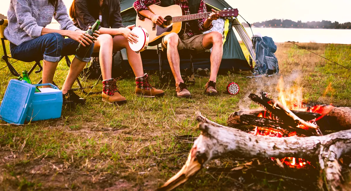 People camping showing their legs sitting around campfire
